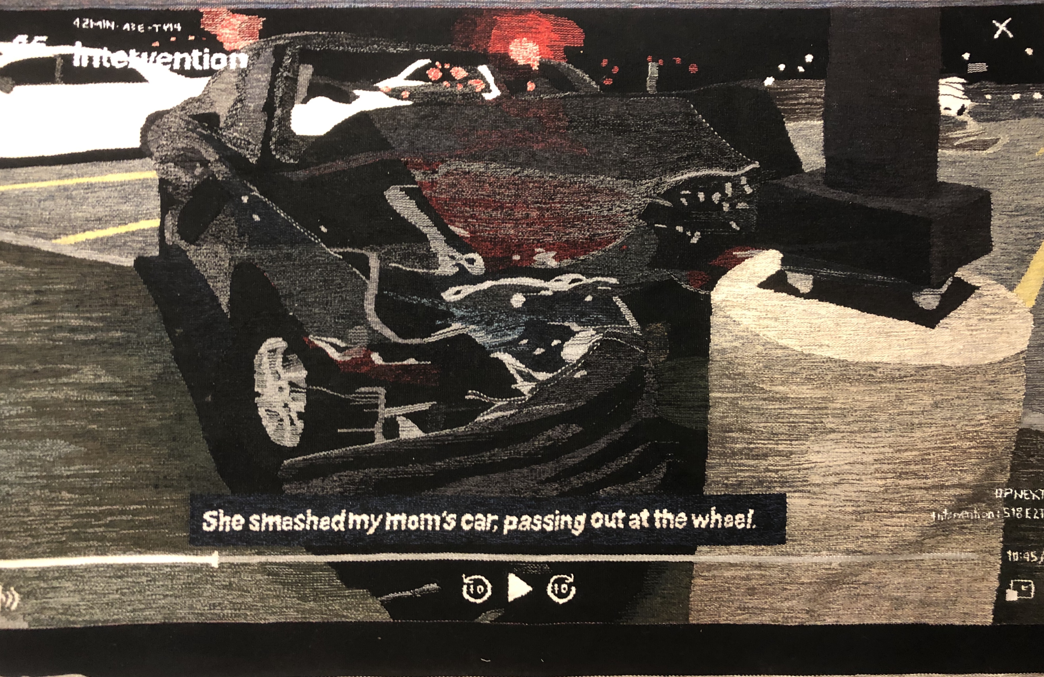 A tapestry depicting a still of a video screen, a car crash with the text "she smashed my mom's car, passing out at the wheel"