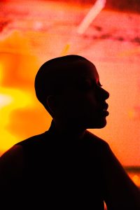 A photograph of a silhouette of a person's head and shoulders against orange light
